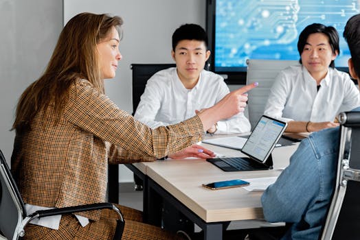 Image of business professionals collaborating around a tablet, discussing IT strategy.