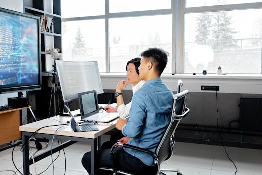 A diverse team of IT professionals collaborating around a digital display showing data analytics and code, representing innovation and teamwork.