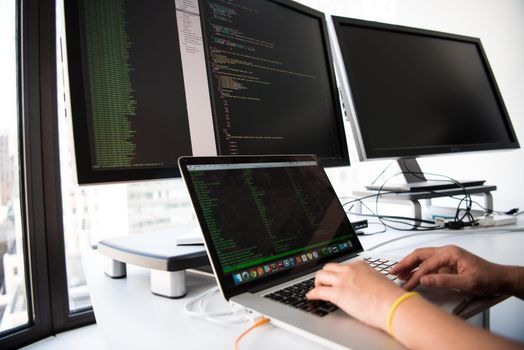 Software development team writing custom enterprise code on multiple monitors